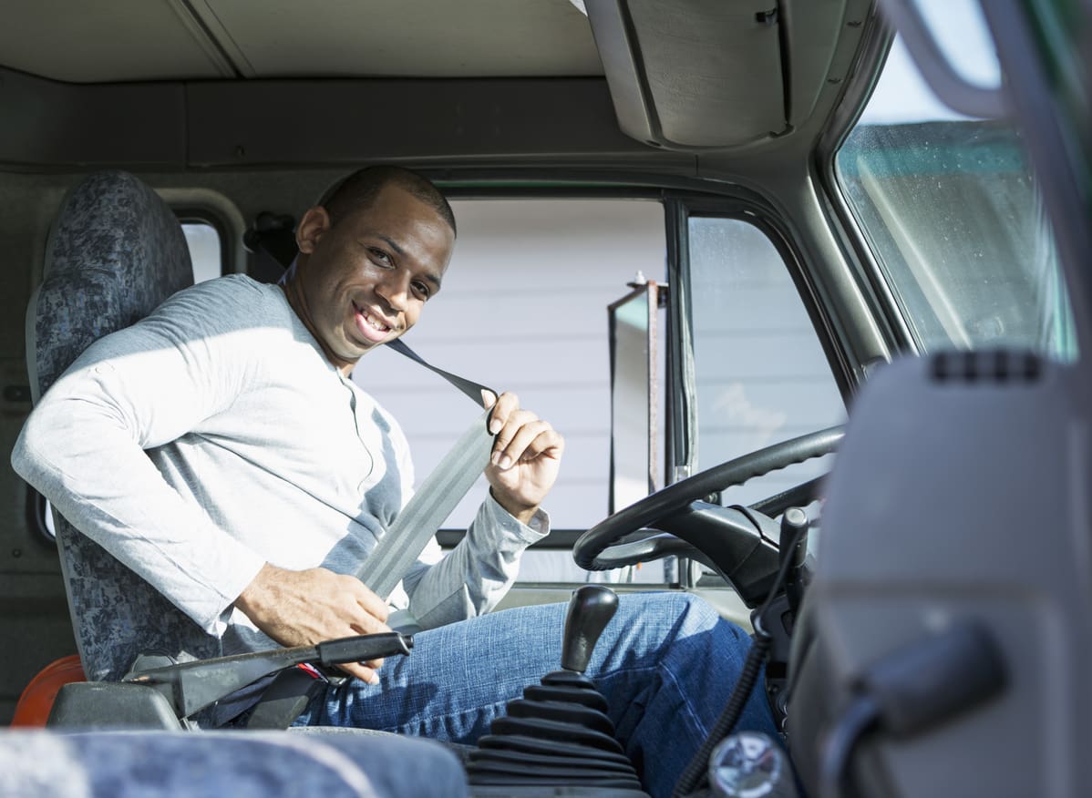 truck driver smiles as he puts on his seatbelt
