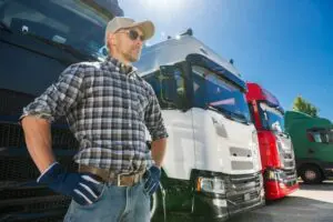 A semi truck driver standing in front of a group of trucks as a member of national trucking organizations