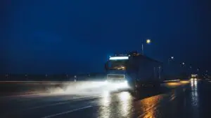Blue Long Haul Semi-Truck with Cargo Trailer Full of Goods Travels At Night on the Freeway Road with limited visibility, which is why TDI doesn't offer CDL classes at night