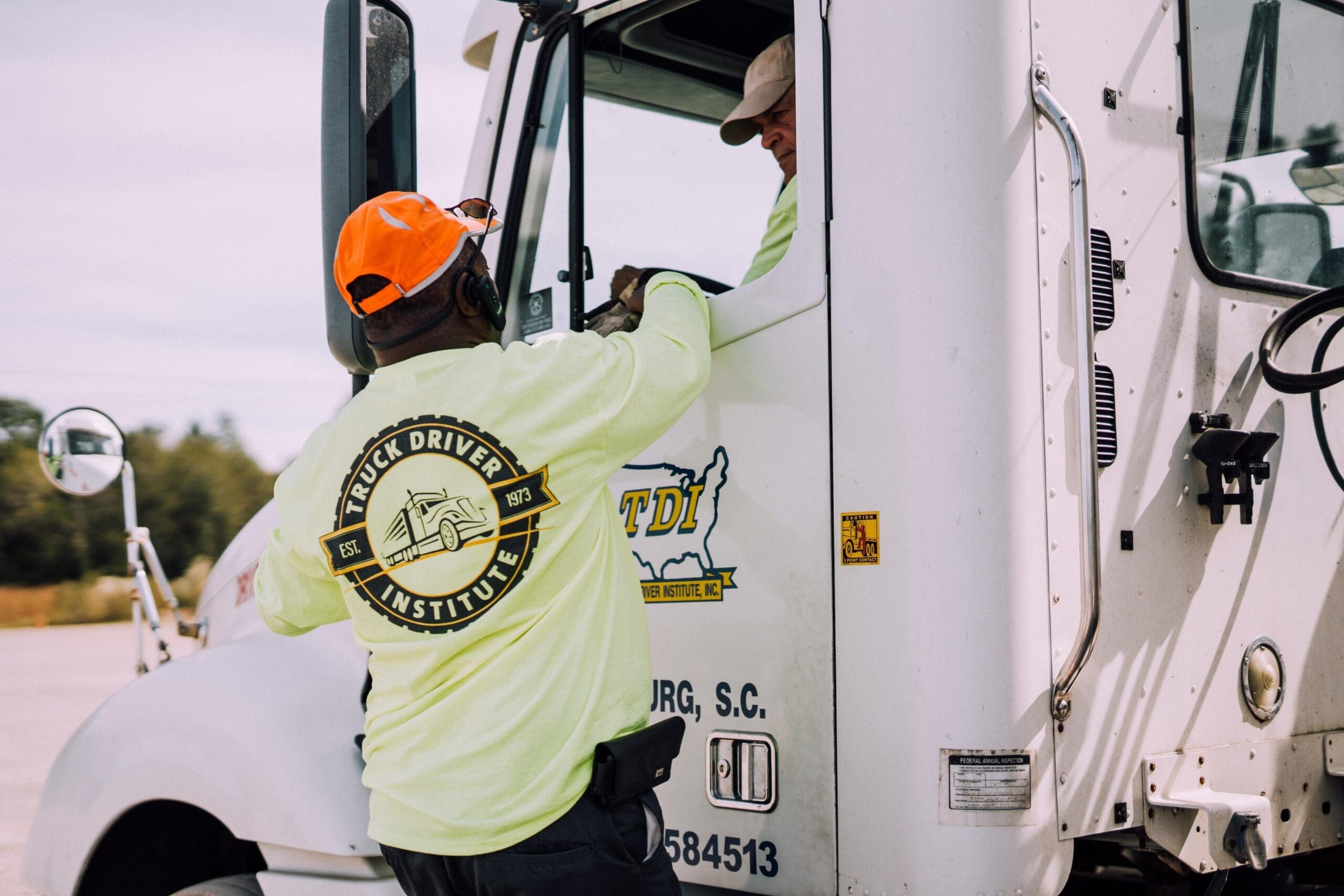 One truck driver talks to another through the window of his truck cab.