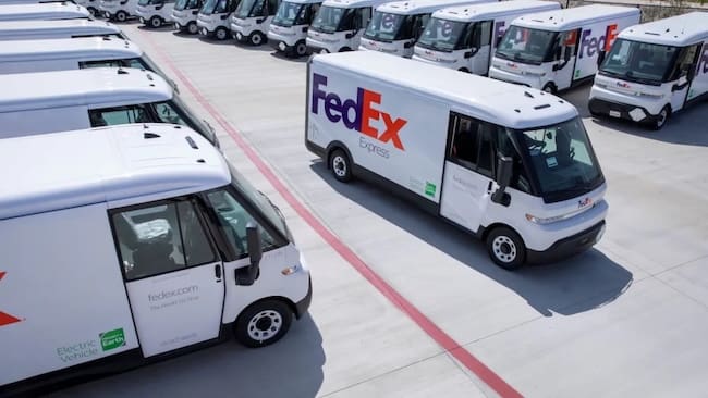 Two rows of parked FedEx Express trucks with one driving off the lot as drivers fulfill their FedEx truck driving careers