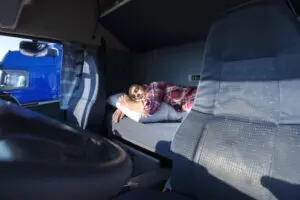 Truck driver sleeping on bed inside truck cabin to show truck driver sleep habits